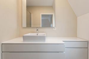 Un baño blanco con lavabo y espejo. en Villa Normandie 22 Gar, en Knokke 11 fotos más