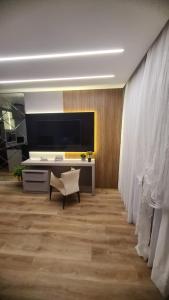 a living room with a television and a desk with a chair at Studio Pomerode in Pomerode