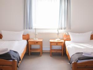two beds in a room with a window and two tables at campushus in Sankt Peter-Ording
