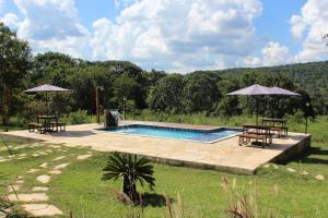 a pool with tables and chairs and umbrellas at Chalé canto da mata in Pirenópolis