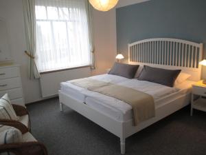 a bedroom with a large white bed with a window at Nordsee Haus An't Oll Deep in Dornumersiel