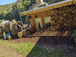 a cabin with a pile of wood next to a deck at Kleine Wohnung am waldrand in Baustert +13 photos