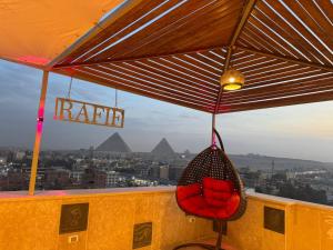 a red chair sitting on a balcony with pyramids at Rafif hotel in Cairo +9 photos