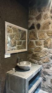 La salle de bains en pierre est pourvue d'un lavabo sur un mur en pierre. dans l'établissement De Sudi Bungalows, à Pemuteran