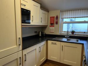 a kitchen with white cabinets and a sink and a window at Haven Hideaway in Harwich