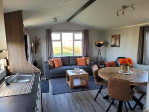 a living room with a couch and a table at Fiets & Relax Chalet in Den Bommel