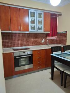 una cucina con mobili in legno e un forno a piano cottura di Noel & Lea Apartment a Ksamil