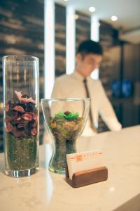 a table with a glass vase with flowers and a card at Golden Stone Hotel in Kaohsiung