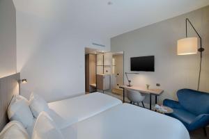 a hotel room with a white bed and a blue chair at NH Roma Villa Carpegna in Rome