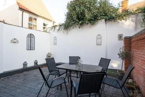 a patio with a table and chairs and a white wall at Juniper House in Harwich
