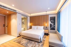 阿拉哈巴德Radisson Hotel Prayagraj的卧室里有一张白色的大床和一张长凳