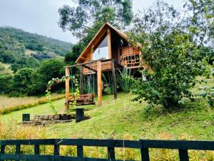 a wooden cabin on a hill with a fence at Glamping El Ocaso in Zipaquirá
