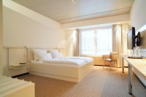 a white bedroom with a bed and a window at Hotel Restaurant Reuter in Rheda-Wiedenbrück