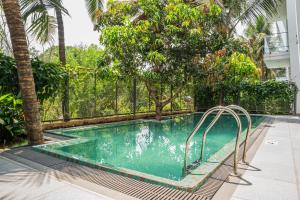 a swimming pool with trees and a fence at Vilmaris Luxury Villas in Saligao