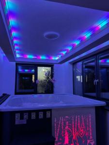 Una habitación con una bañera con luces moradas y rosas. en Pensiunea Agroturistică Victoria Mărișel, en Mărişel