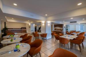 a restaurant with white tables and orange chairs at Relais Manfredi in Castellammare di Stabia