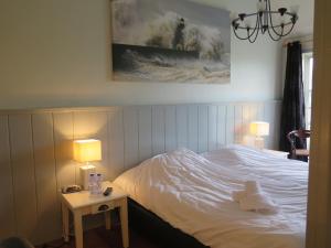 a bedroom with a bed and a table with two lamps at Caf&eacute; Brasserie Het Heerenhuis in Het Kalf
