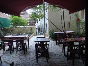un patio con mesas, sillas y una sombrilla en Hotel Des Arts, en Puybrun