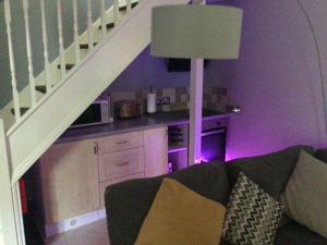 a living room with a couch and a kitchen under a staircase at The Bakehouse in Harwich