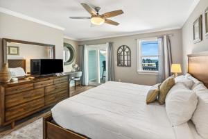 una camera da letto con un grande letto bianco e una televisione di Good Times and Tan Lines a Saint Joe Beach
