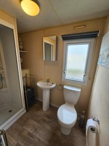 a bathroom with a toilet and a sink and a window at Golden Sands 8 berth cosy caravan in Rhyl