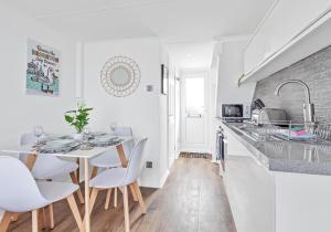 a white kitchen with a white table and chairs at On the Water 3 with Free Parking By My Getaways in Brighton & Hove
