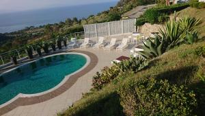 een zwembad op een heuvel met stoelen en de oceaan bij Luxury Villa with Pool and Garden in Ricadi +8 foto's