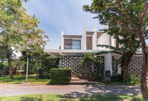 a house with a stone wall and trees at Ocenami Resort 3 pn in Long Hai