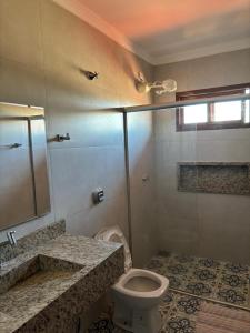 a bathroom with a toilet and a glass shower at Flat Bonito Jarinu 02 Centro in Bonito +2 photos