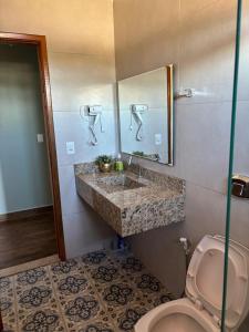 a bathroom with a sink and a toilet and a mirror at Flat Bonito Jarinu 02 Centro in Bonito