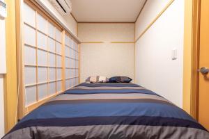 Y's INN MaisonRose 106T في طوكيو: سرير في غرفة ذات نافذة كبيرة