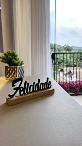 a sign on a bed in a room with a balcony at Studio Pomerode in Pomerode