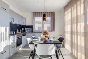a kitchen with a dining table and white chairs at Apartment B10 "Südbalkon mit Haffblick" im Pine Hill Resort in Zirchow