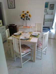 een witte eettafel met stoelen en een tafel met borden en glazen bij Casa Fontana in Arcola