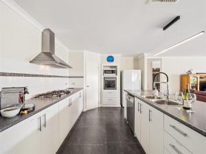 a kitchen with white cabinets and stainless steel appliances at Busselton Broadwater Holiday Home in Busselton