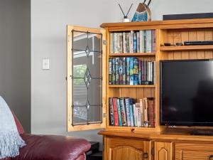 a wooden entertainment center with a television and books at Busselton Broadwater Holiday Home in Busselton