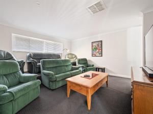 a living room with green couches and a coffee table at Busselton Broadwater Holiday Home in Busselton