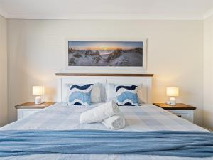 a bedroom with a large bed with blue and white pillows at Busselton Broadwater Holiday Home in Busselton
