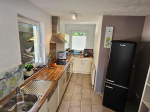 a kitchen with a black refrigerator and a sink at STHS79005-FeWo-Meerruschen in Meeschendorf