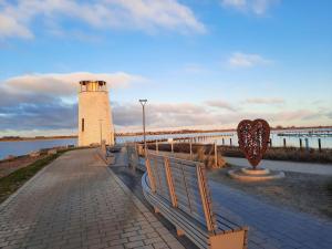 ein Leuchtturm und eine Bank neben einem Wasserkörper in der Unterkunft MEHS3E001 in Meeschendorf