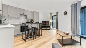 a kitchen and living room with white cabinets and a table at JD Apartments Skyview 1BR in South Norwood