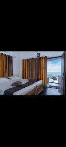 a bedroom with two beds and a large window at Sandcastle Resort in Varkala
