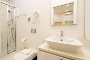 a white bathroom with a sink and a shower at GuestReady - Port Studio 4 in Bandeira +6 photos