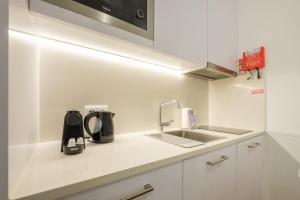 a white kitchen with a sink and a microwave at GuestReady - Port Studio 4 in Bandeira