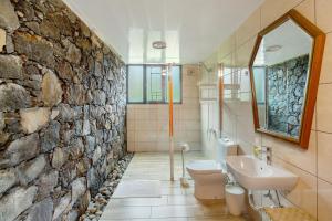 a bathroom with a stone wall and a toilet and sink at Refugio Da Xamusca in São Vicente +19 photos