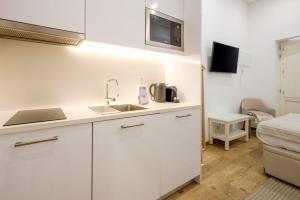 una cucina con armadi bianchi, lavandino e letto di GuestReady - Port Studio 3 a Vila Nova de Gaia