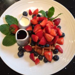 un plato blanco con fresas, arándanos y gofres en AmarAgua Guest house, en Edimburgo