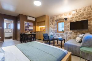 a bedroom with a bed and a kitchen with a table at Studio Suites Mila in Komiža