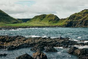 a person sitting on some rocks in the water at Portrush Adelphi in Portrush