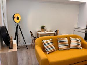 a living room with a yellow couch and a table at Valma GuestHouse in Viana do Castelo